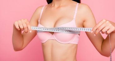 Cropped close-up photo of nice cute adorable attractive cheerful positive optimistic girl in beige bra measuring chest size line with tape isolated over pink background